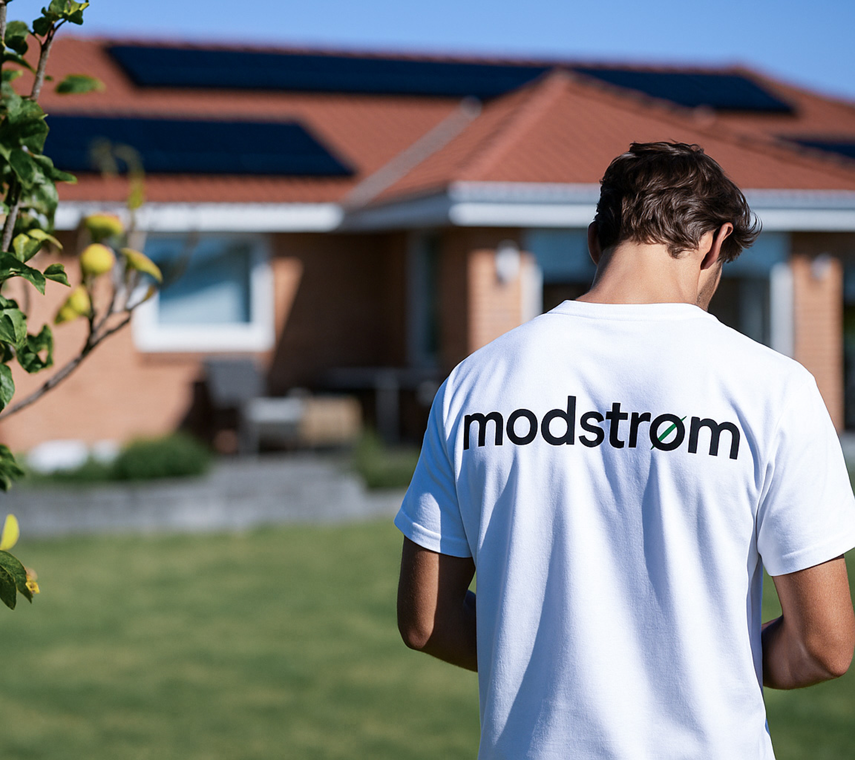 Person i t-shirt med Modstrøm-logo på foran hus med solceller på taget